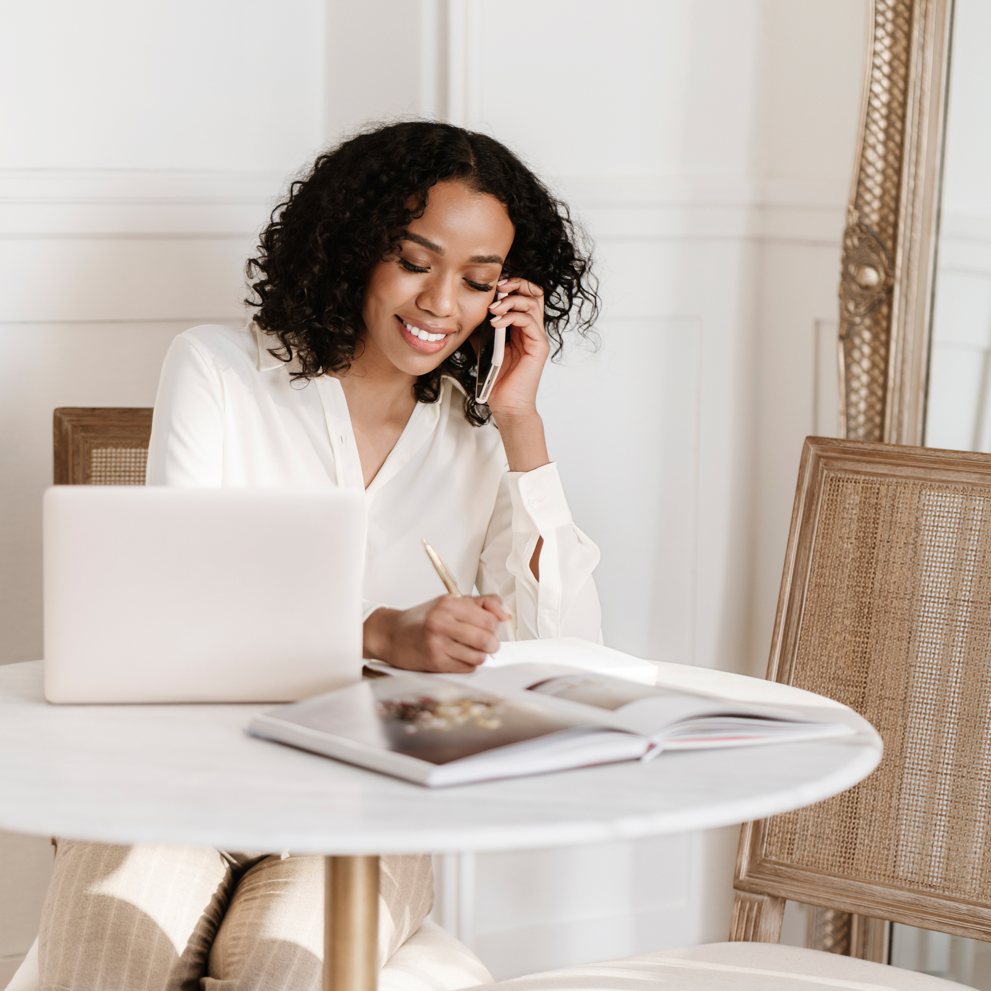 A woman at her computer talking on the phone, multitasking and managing tasks—representing effective delegation for business efficiency.