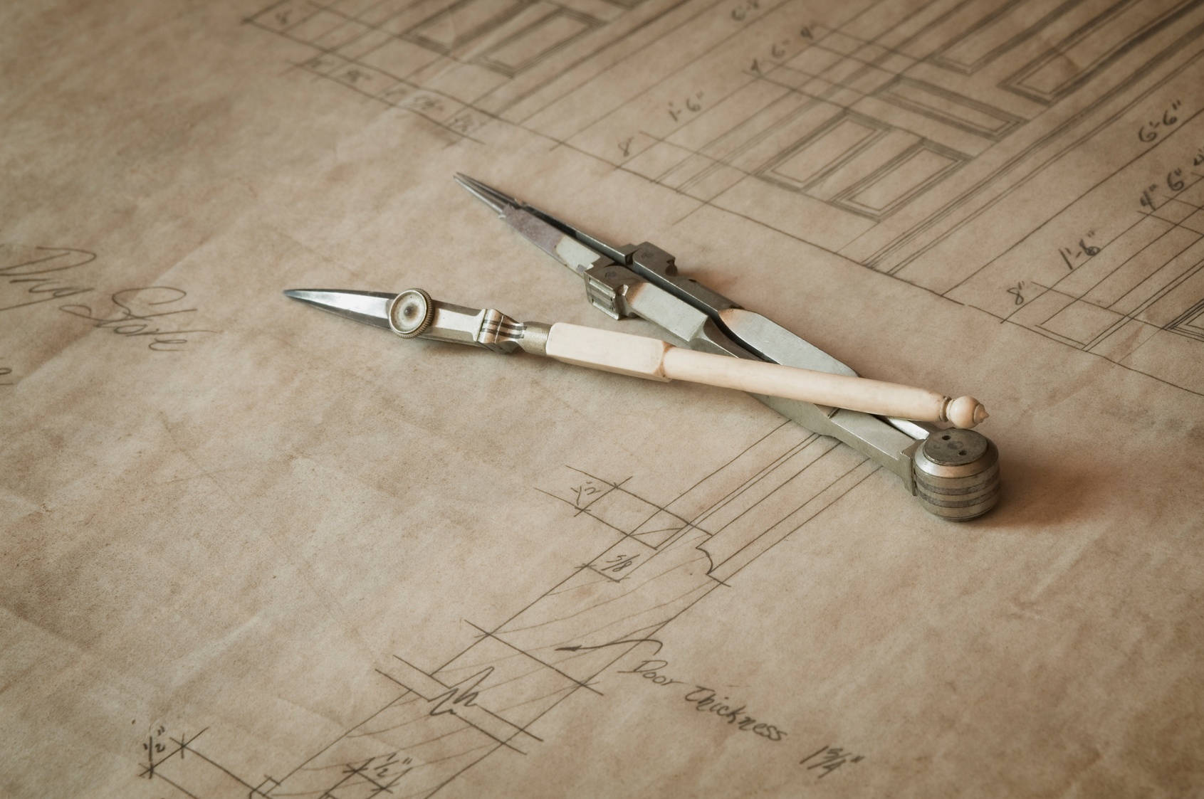 Antique drafting compass resting on architectural plans, symbolizing strategic planning for business credit and bonding