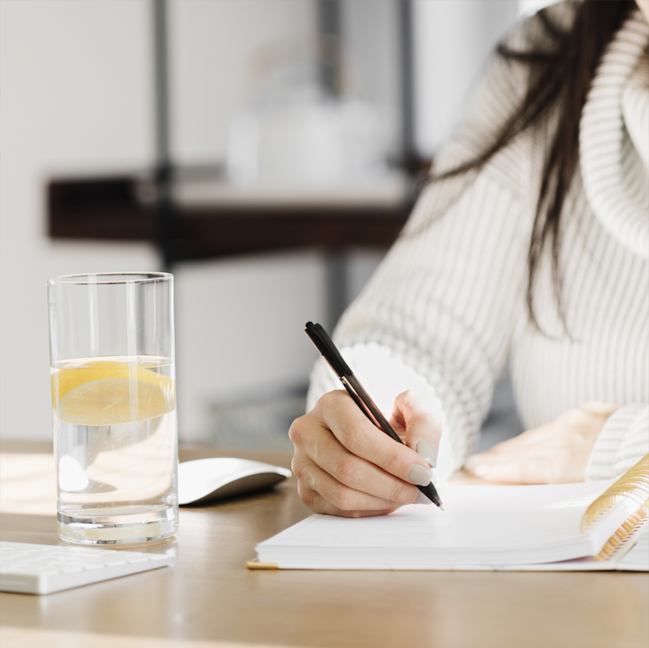 Entrepreneur’s desk with open planner, financial reports, and water—representing intentional financial review